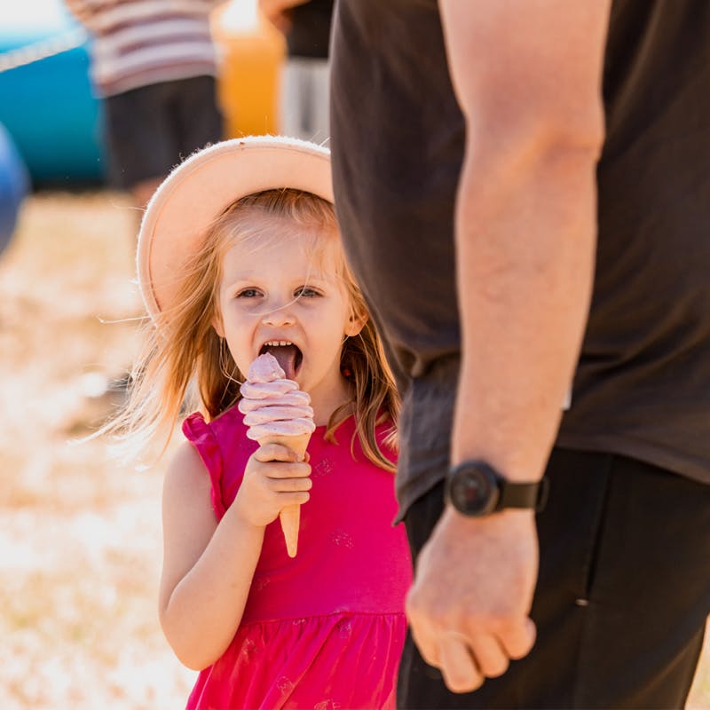Small kid enjoying ice cream with her dad at the event